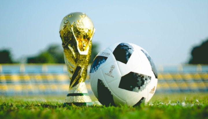 Ball and Golden Cup on Green Football Pitch